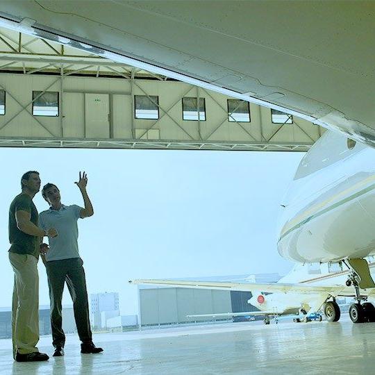 Two men standing beside a private jet discussing business aviation mro services