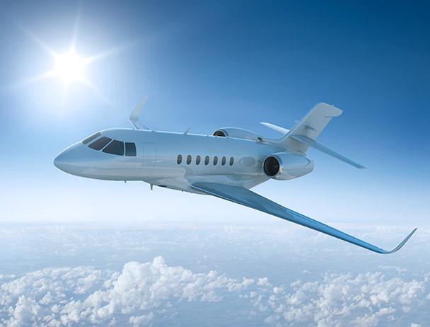 私人商务飞机在阳光普照的天空中飞过云层